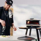 Chef seasoning a pizza beside the Gozney Arc XL in Bone