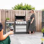 Woman cooking on the Napoleon Prestige PRO 500 Built-In while friends relax with wine