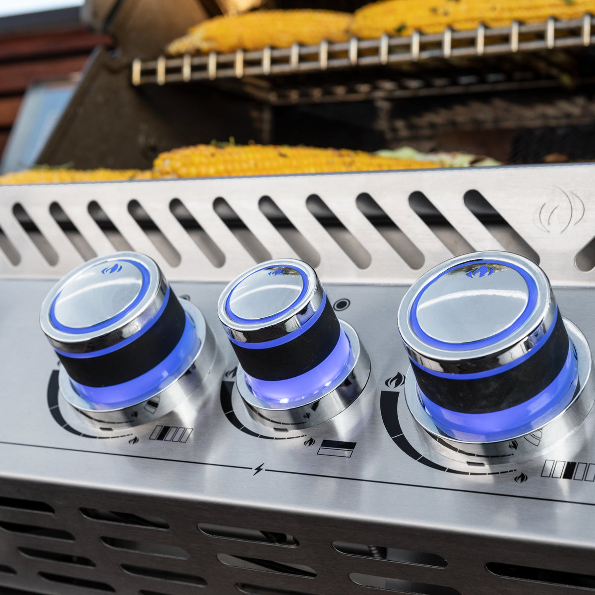 Lit control knobs on the Napoleon Prestige PRO 665 Built-In with food on the grill