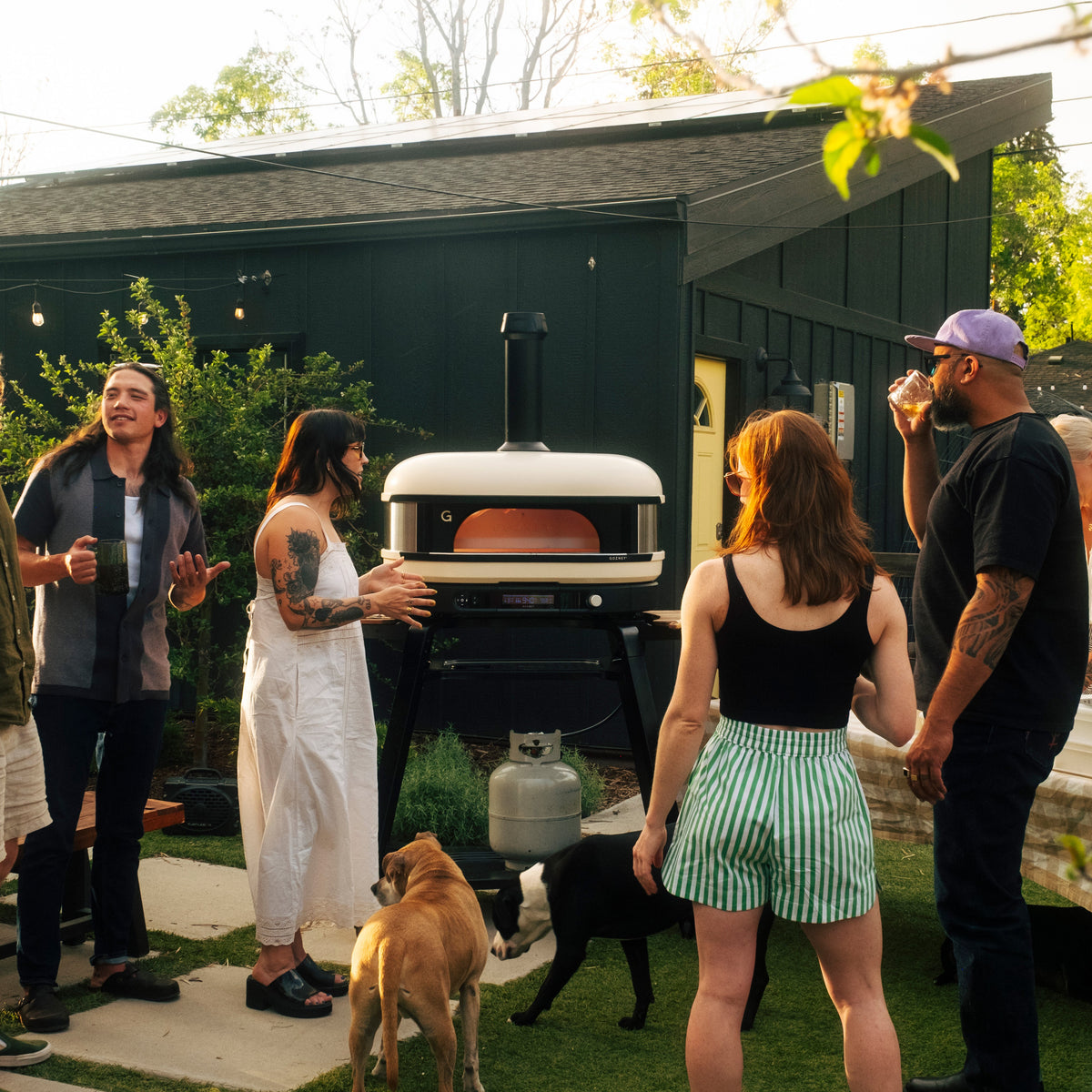 Friends and a dog gathered around the Gozney Dome XL (Gen 2) in a garden
