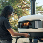 Woman cooking with the Gozney Dome (Gen 2) in Bone outdoors