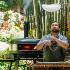 Chef stretching pizza dough beside the Gozney Dome XL (Gen 2) in Off Black