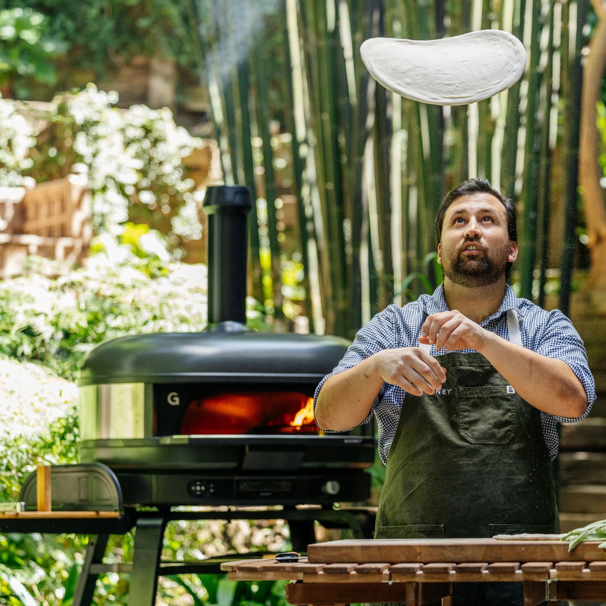 Chef stretching pizza dough beside the Gozney Dome XL (Gen 2) in Off Black
