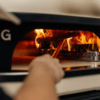 Pizza being turned beside the flames in the Gozney Dome XL (Gen 2)
