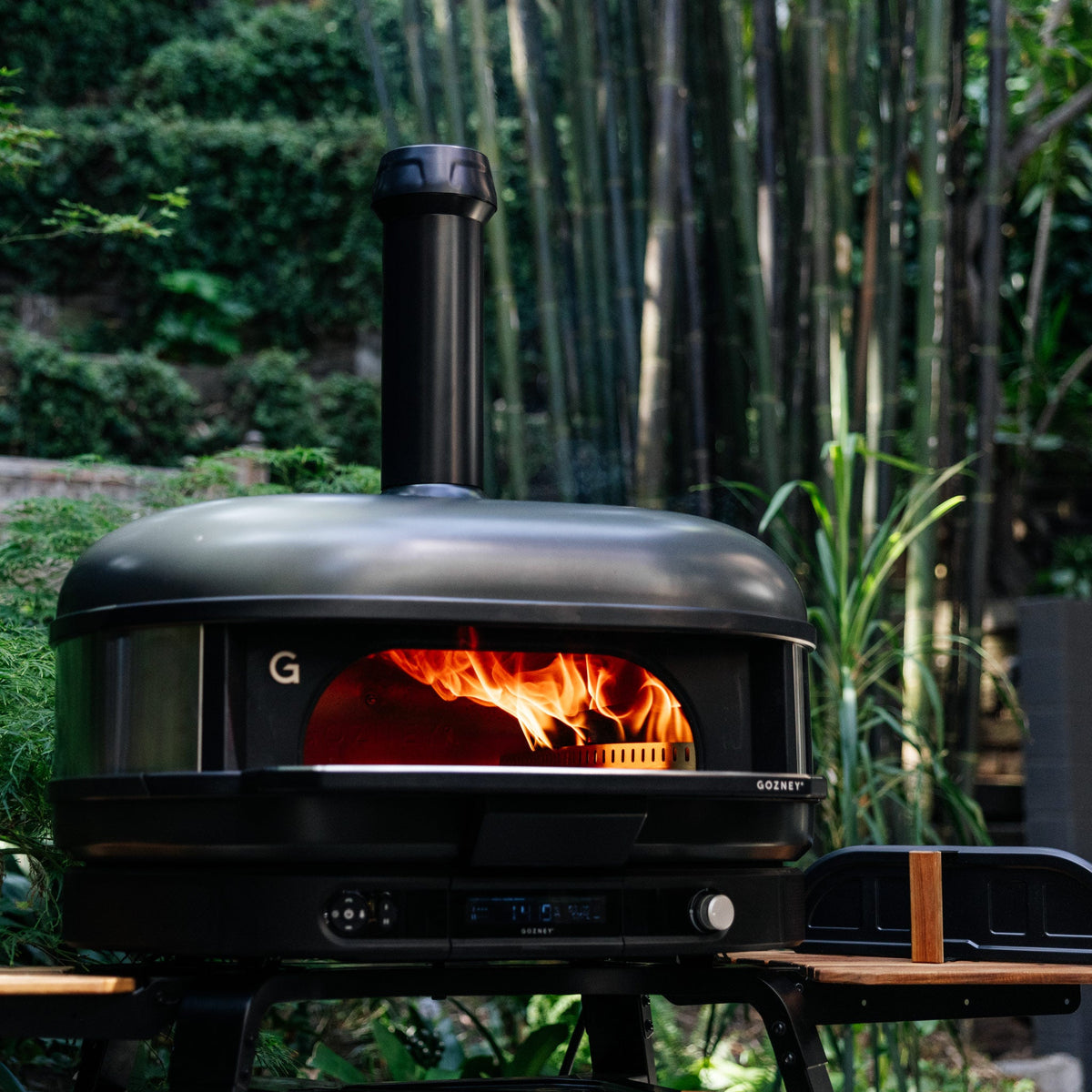 Wood fire burning in the Gozney Dome XL (Gen 2) in Off Black in a bamboo garden