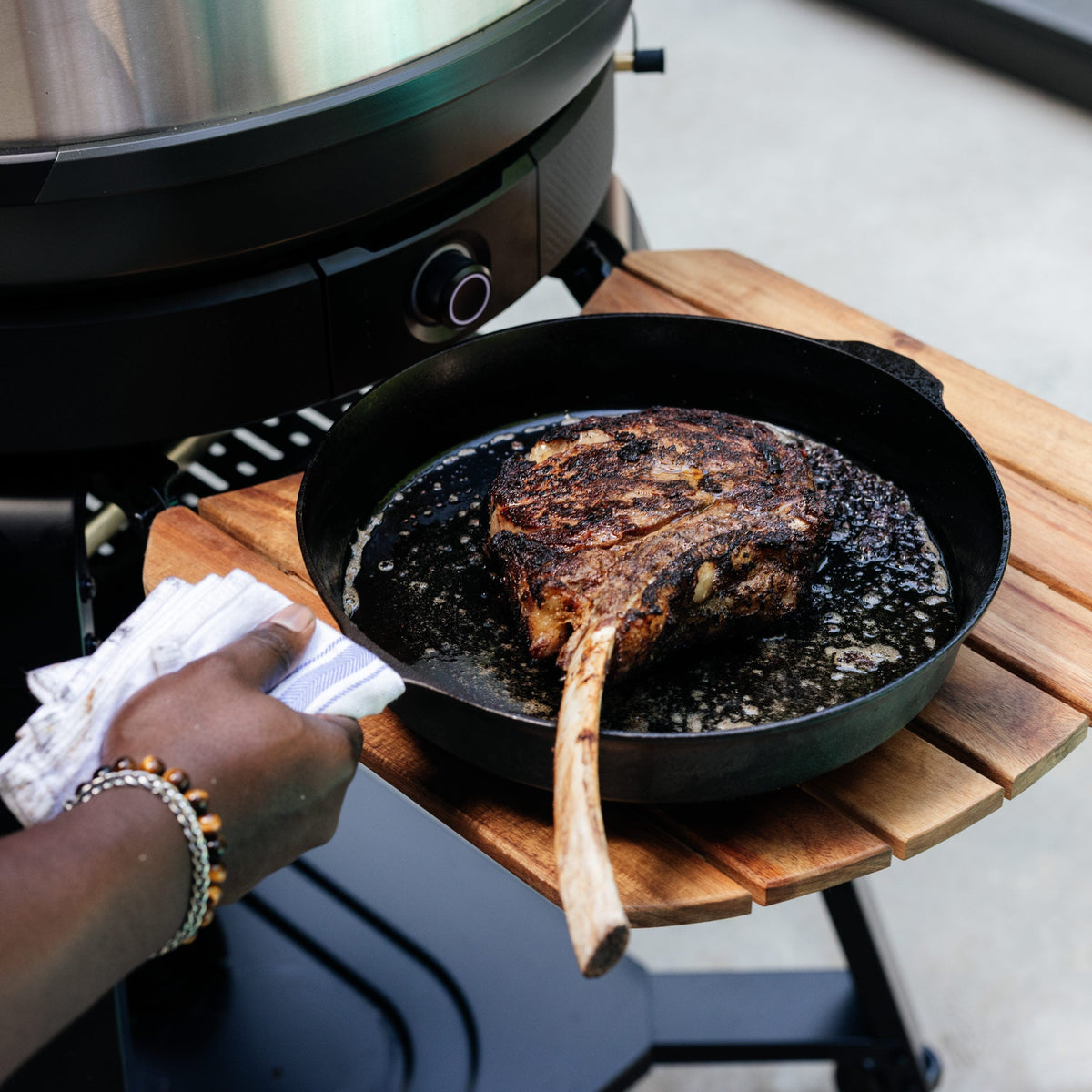 Steak in a pan on the wooden side shelf of the Gozney Dome (Gen 2) Stand