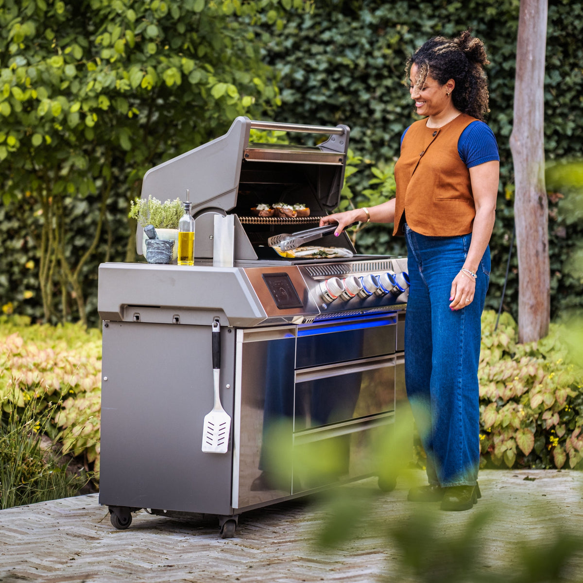 Woman cooking on the Napoleon Prestige PRO665 Elite Smart in a garden