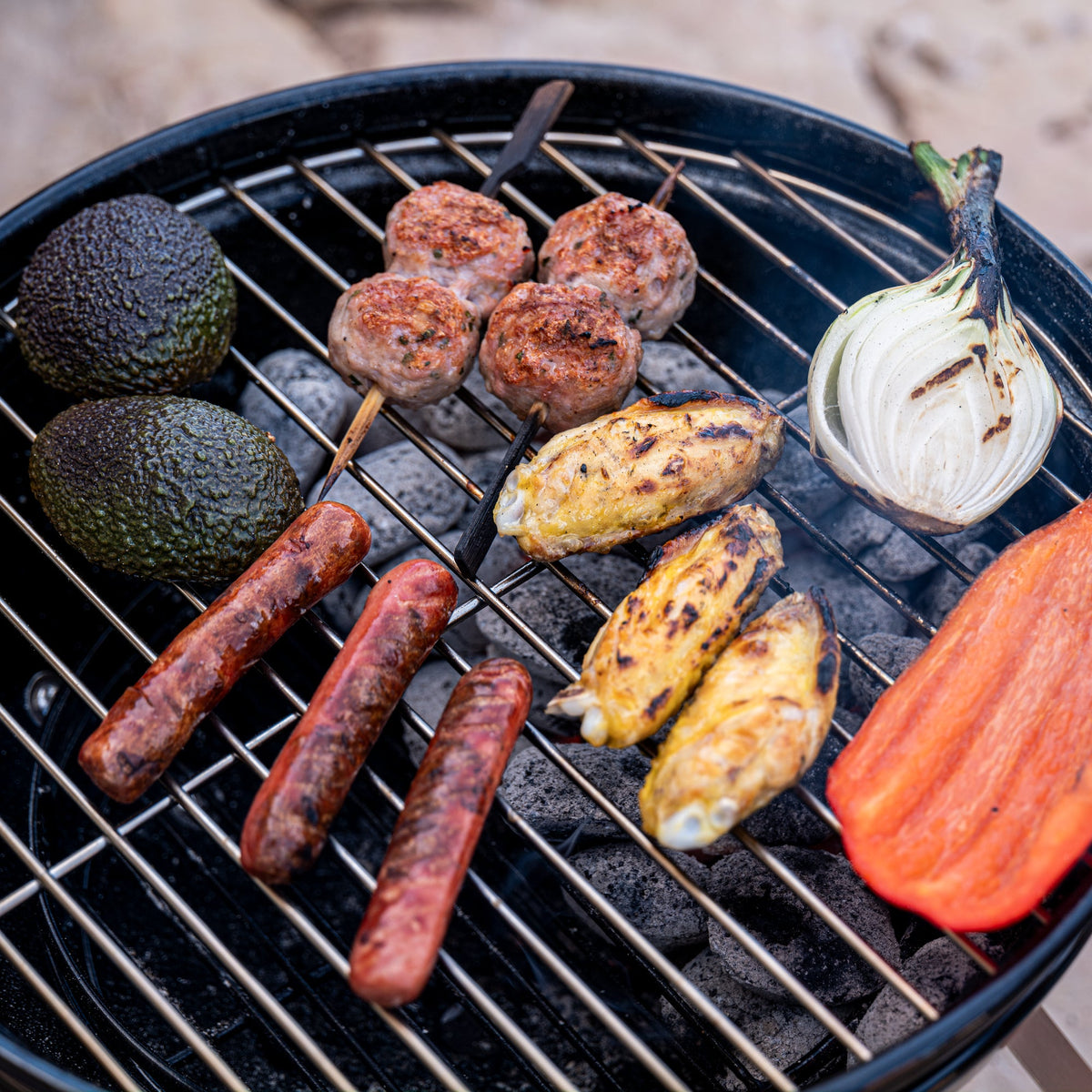 Sausages, meatballs and vegetables grilling over charcoal on the Napoleon NK14