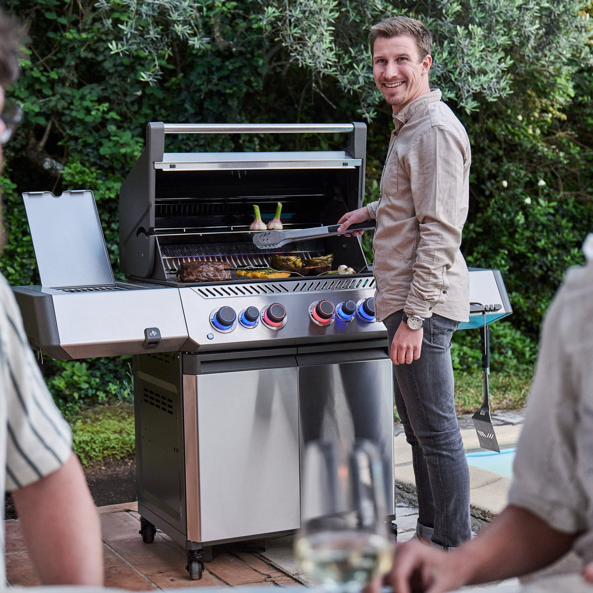 Man grilling for friends on the Napoleon Prestige 500 Connected Gas BBQ