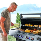 Man grilling corn and skewers on the Napoleon Prestige 500 Phantom Connected with a lake view
