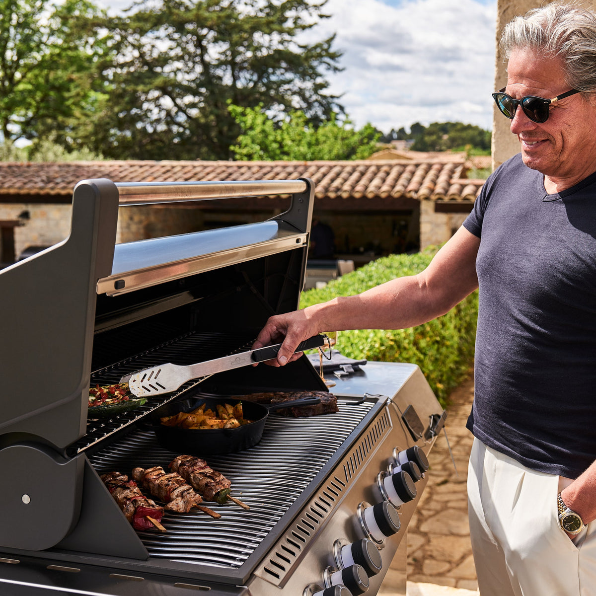 Man grilling meat and kebabs on the Napoleon Prestige 665 Connected Gas BBQ