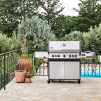 Napoleon Prestige 665 Connected Gas BBQ on a stone terrace beside a swimming pool