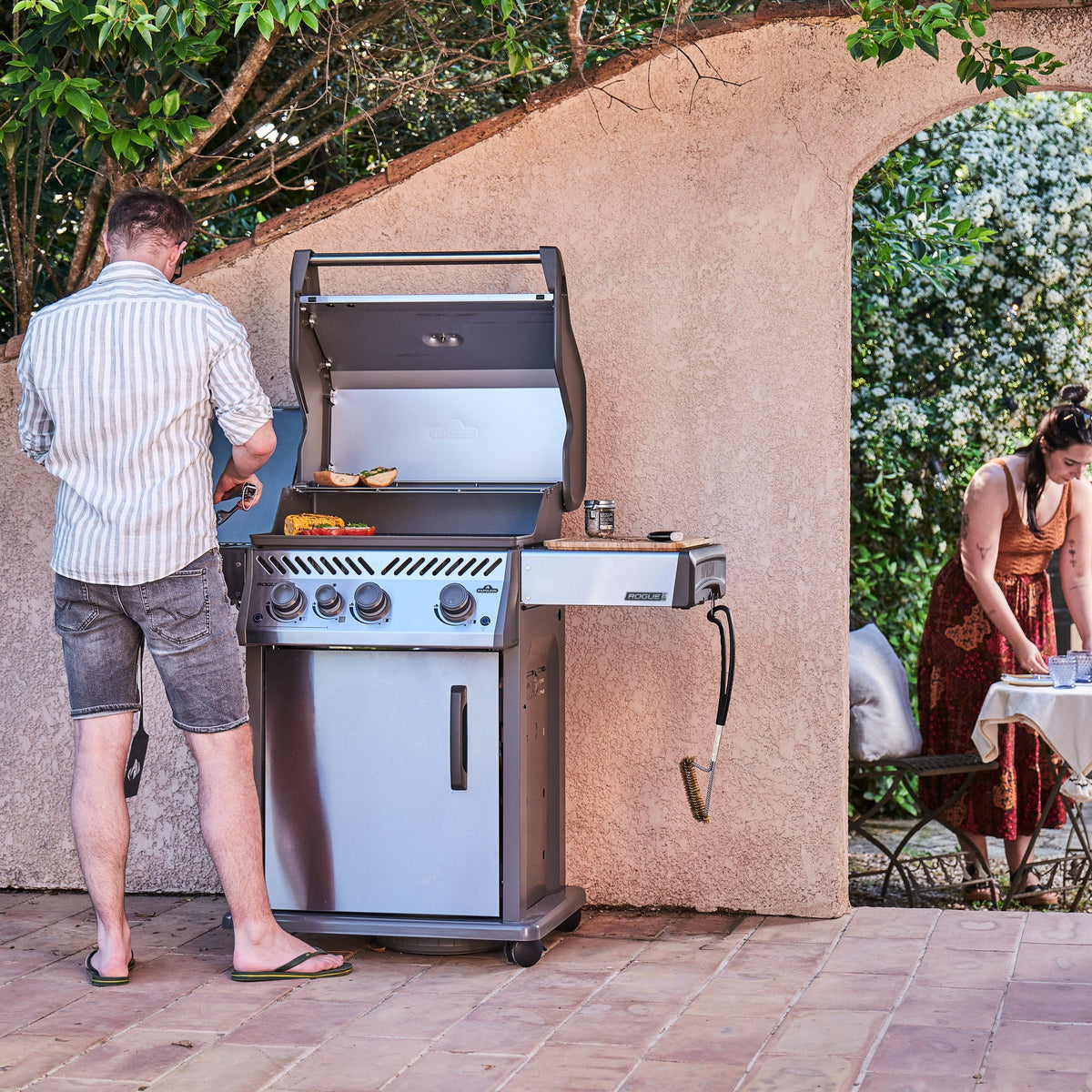 Man cooking on the Napoleon Rogue PRO 425 SIB while friends sit at a table