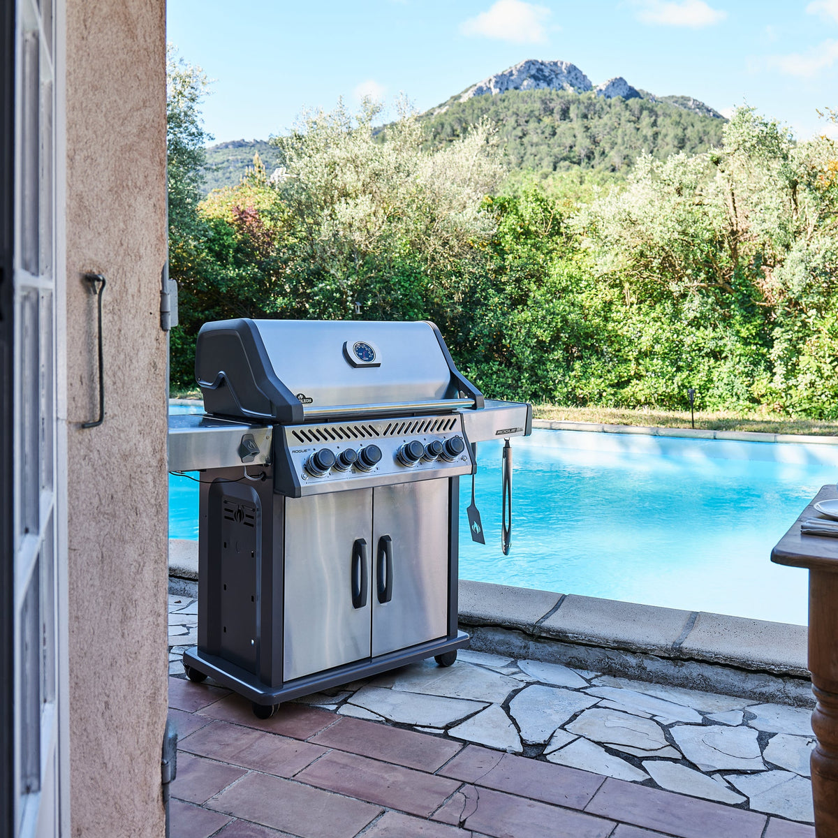 Napoleon Rogue PRO-S 525 Gas BBQ beside a swimming pool with hills behind